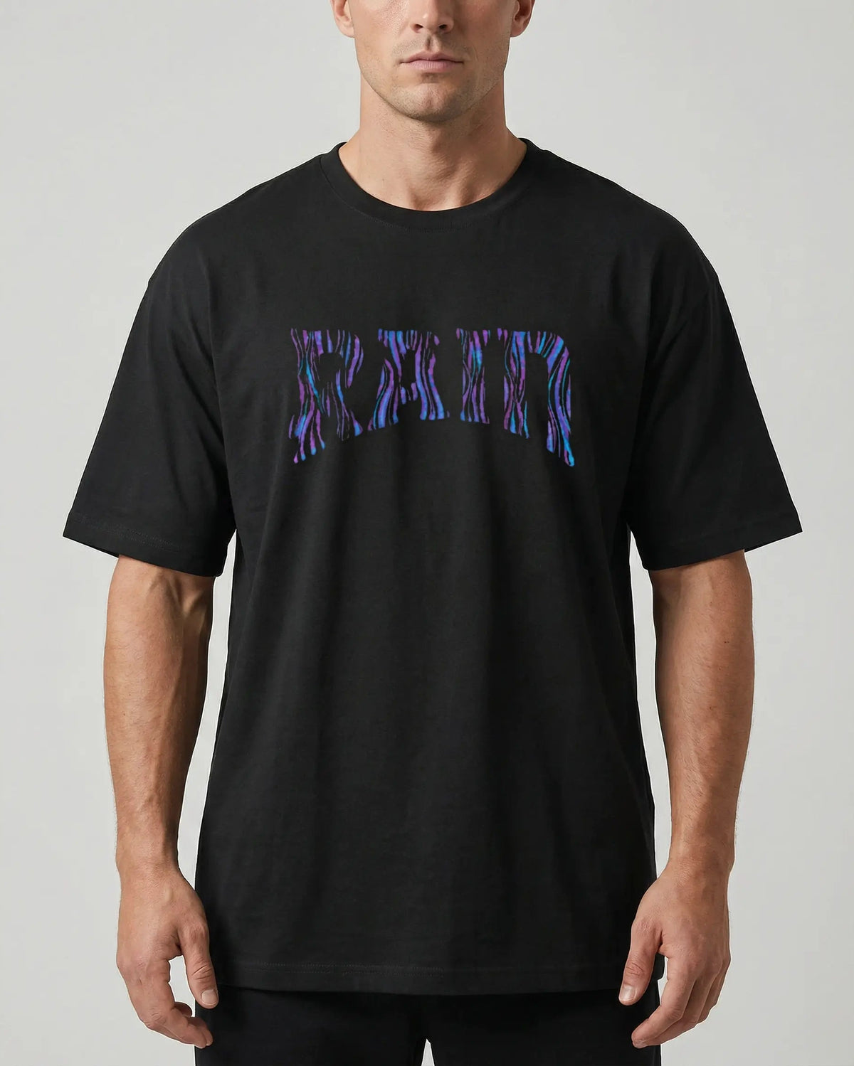 A man wearing a black crewneck t-shirt with a stylized 'GRAM' graphic across the chest in a blue and purple textured pattern, shot against a neutral gray background.