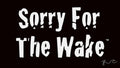 A black flag or banner with the phrase 'Sorry For The Wake' printed in large white stylized lettering. A white hanging edge with grommets is visible along the left side, and a small white script mark appears in the lower right corner.